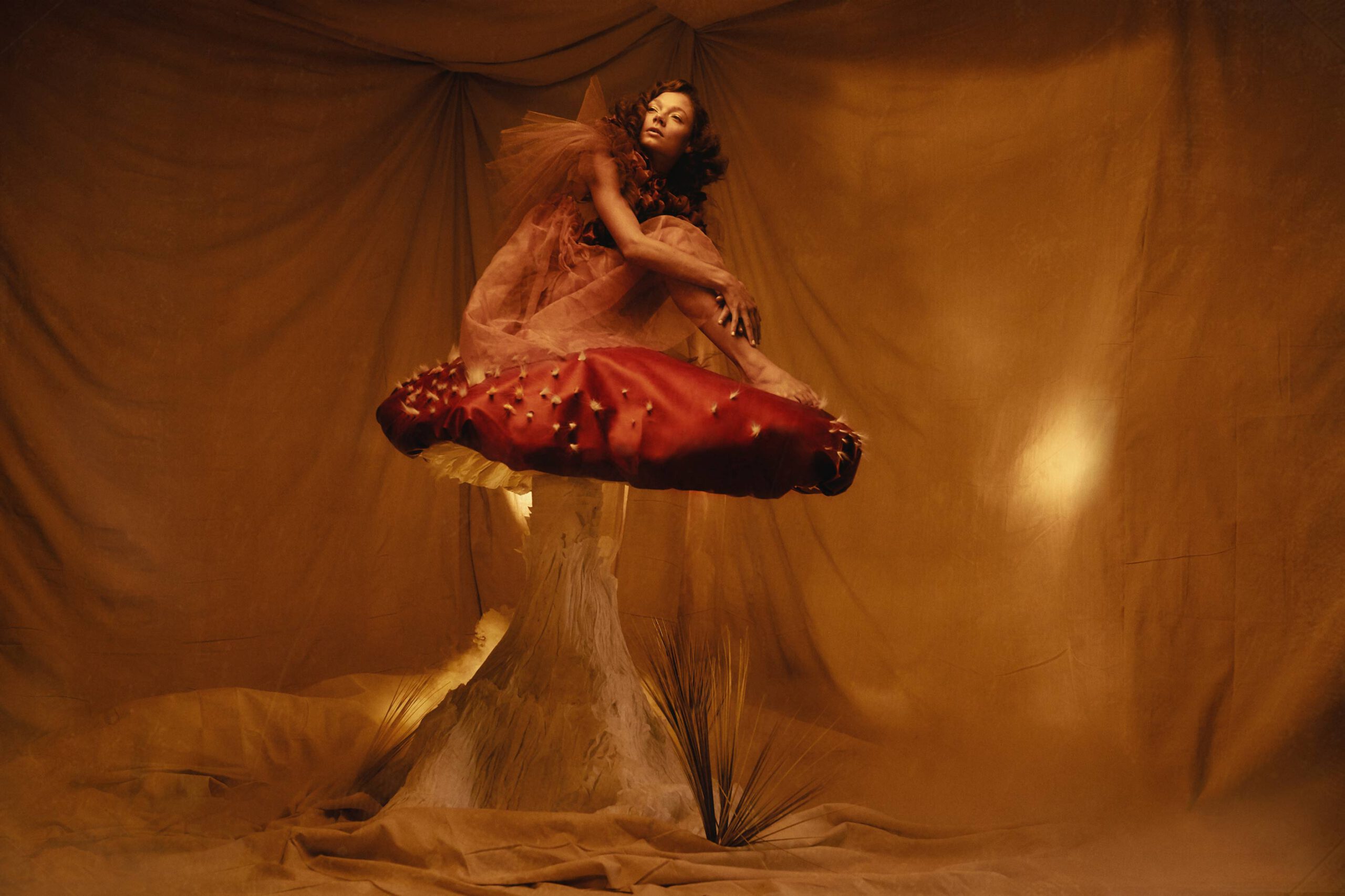 Dariane Sanche Photographe professionnelle spécialisée en photo editorial mode et creative. Photo d'une femme assise sur un champignon géant avec de la fumé au sol.
