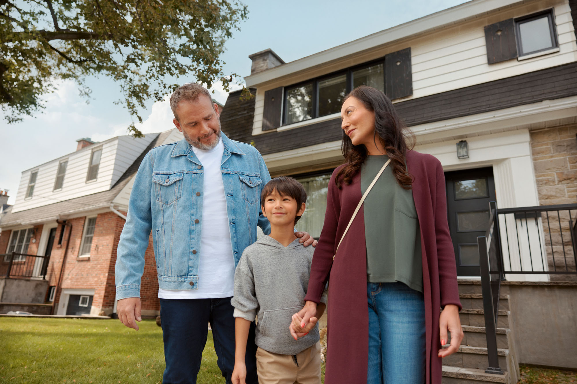Photographie d'une jeune famille se tenant sur la pelouse devant leur maison