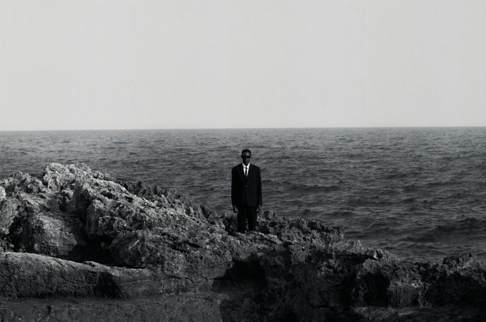 Photographie mode et storytelling d'un homme d'affaire en sicile qui entre dans la méditéranée avec son suit noir et blanc